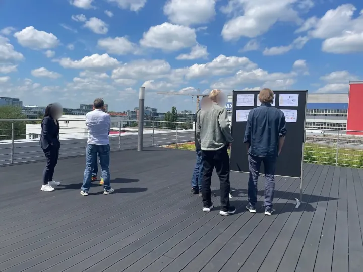 People working at outdoor standing boards during a workshop—serious collaborative work, not celebration.